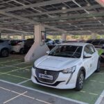 Coche el&eacute;ctrico en un aparcamiento con paneles solares