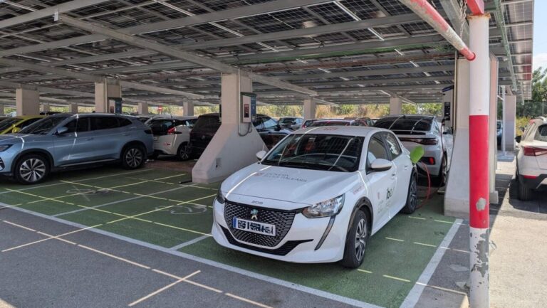 Coche el&eacute;ctrico en un aparcamiento con paneles solares