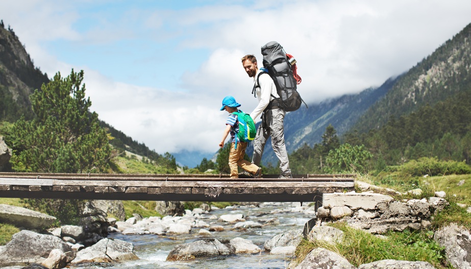 Padre e hijo cruzando un puente en un entorno natural monta&ntilde;oso