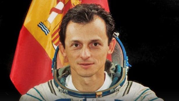 Pedro Duque, primer astronauta español, con traje espacial y bandera de España.
