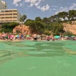 Vista de la playa de s'Oratori en Portals Nous con gente disfrutando del sol.