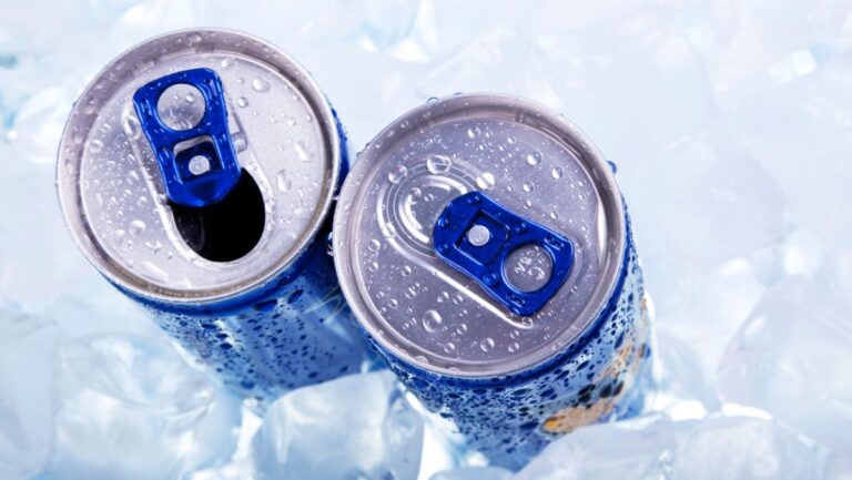 Dos latas de bebida energética sobre hielo con gotas de agua